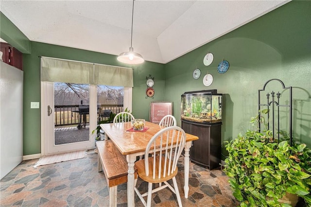 dining area with stone finish floor and vaulted ceiling