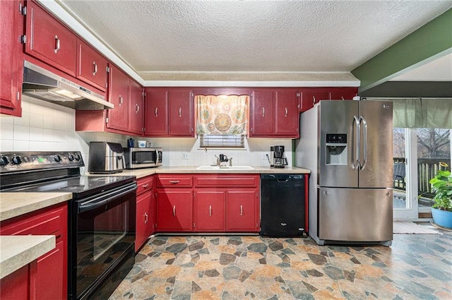 kitchen featuring red cabinets, tasteful backsplash, a sink, under cabinet range hood, and black appliances