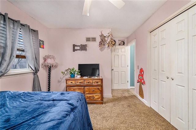 carpeted bedroom with baseboards, visible vents, a ceiling fan, a textured ceiling, and a closet