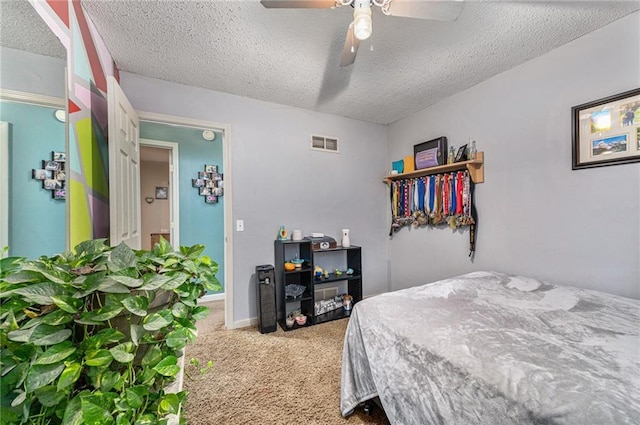 carpeted bedroom featuring a ceiling fan, visible vents, a textured ceiling, and baseboards