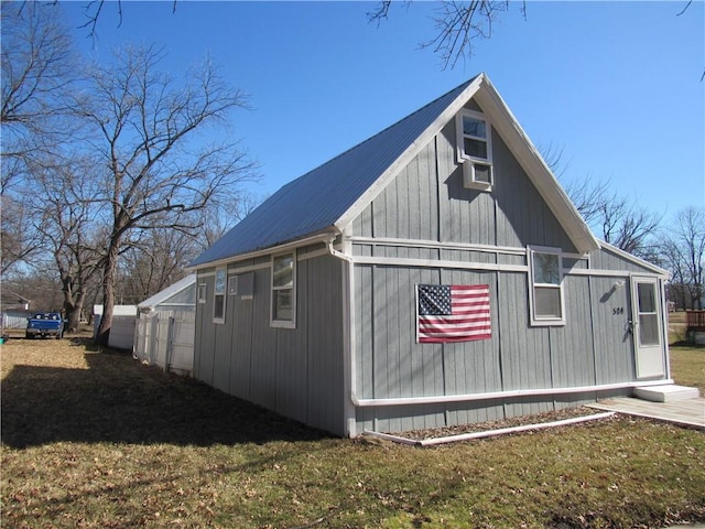 view of side of property featuring a yard, cooling unit, and metal roof