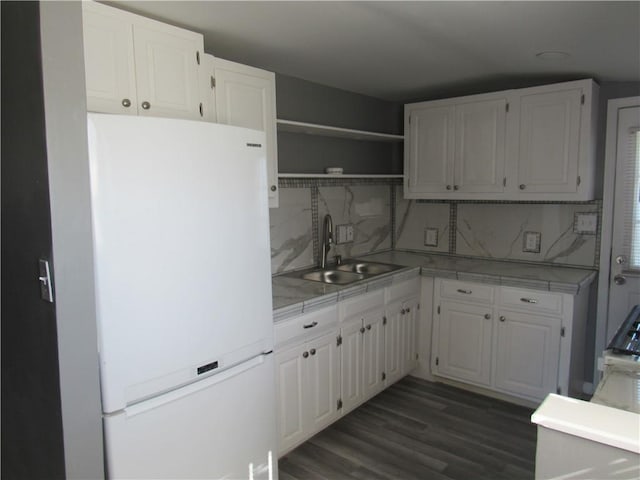 kitchen with light countertops, freestanding refrigerator, white cabinetry, and a sink