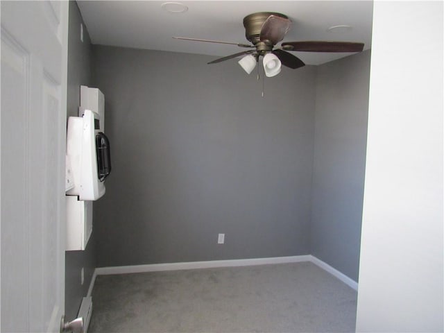 carpeted empty room featuring ceiling fan and baseboards