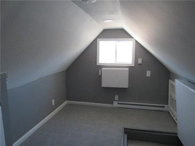 additional living space with a baseboard heating unit, carpet, lofted ceiling, and baseboards