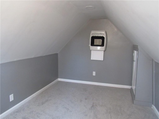 additional living space featuring light colored carpet, baseboards, vaulted ceiling, and heating unit