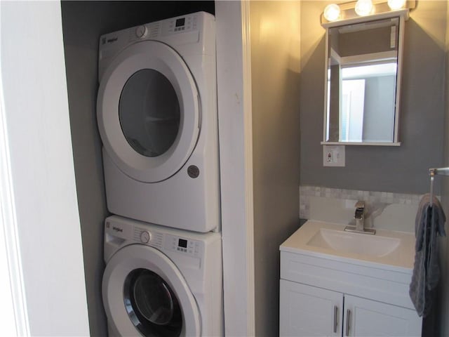 laundry area with stacked washing maching and dryer, laundry area, and a sink