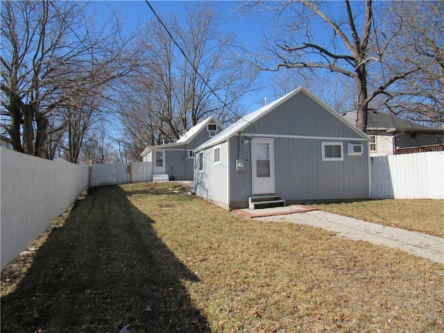 view of home's exterior featuring entry steps, a lawn, driveway, and fence private yard