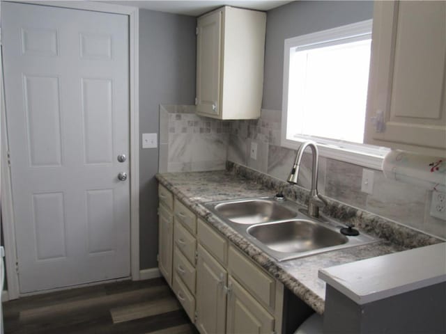 kitchen featuring dark wood-style flooring, light countertops, backsplash, cream cabinets, and a sink