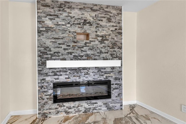 details featuring a glass covered fireplace and baseboards