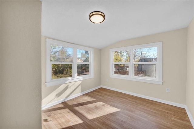 unfurnished room with lofted ceiling, baseboards, and wood finished floors