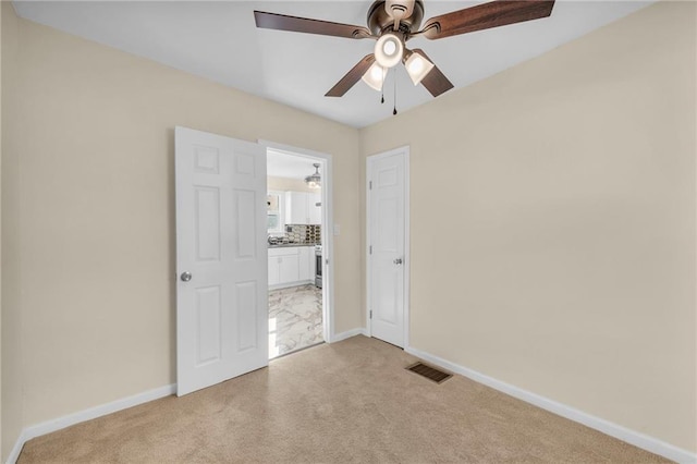 unfurnished bedroom featuring light carpet, a ceiling fan, visible vents, and baseboards