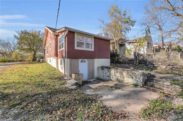 view of property exterior featuring a lawn, a patio area, and fence