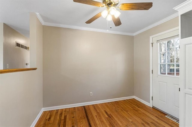 interior space with ornamental molding, wood finished floors, visible vents, and baseboards