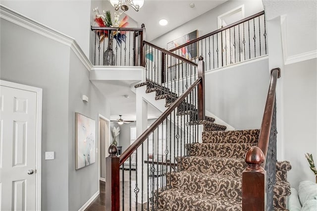 stairs with a high ceiling, wood finished floors, and baseboards