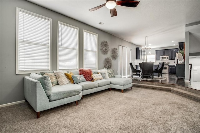 living room with visible vents, dark carpet, ceiling fan with notable chandelier, and baseboards