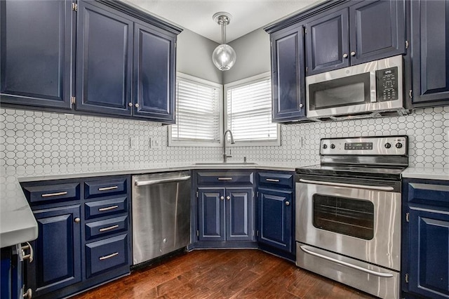 kitchen with a sink, backsplash, blue cabinetry, stainless steel appliances, and dark wood-style flooring