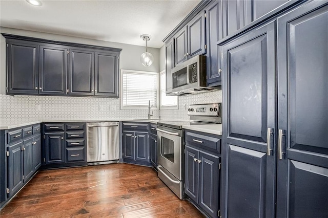 kitchen with backsplash, dark wood-type flooring, light countertops, stainless steel appliances, and a sink