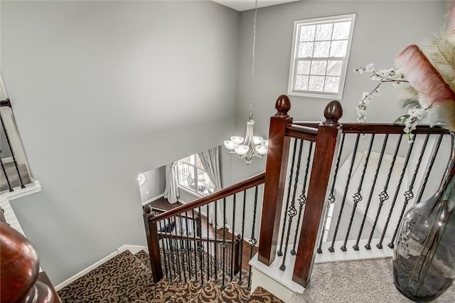 stairs featuring baseboards, carpet floors, and a chandelier