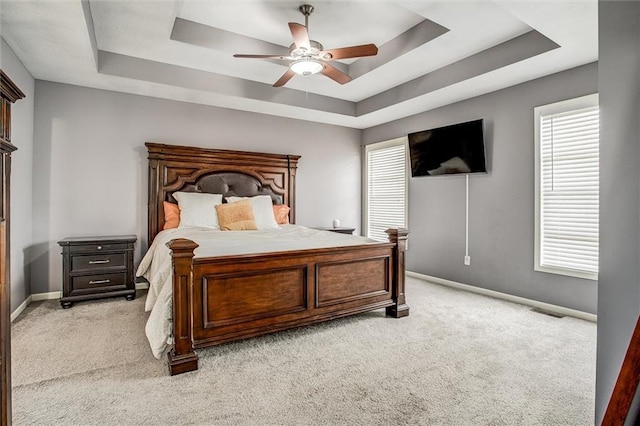 bedroom featuring light carpet, visible vents, baseboards, and a tray ceiling