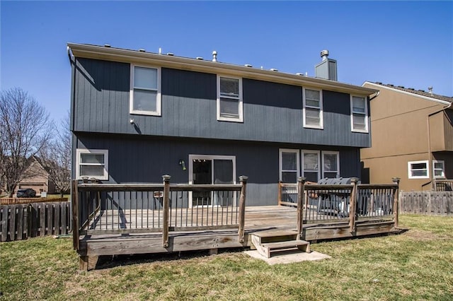 back of property featuring a deck, a chimney, a yard, and fence