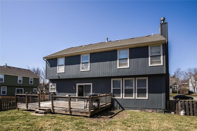 rear view of house featuring a yard, a deck, a chimney, and fence