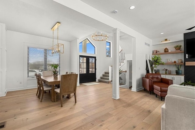 dining space with visible vents, light wood finished floors, stairs, french doors, and a chandelier