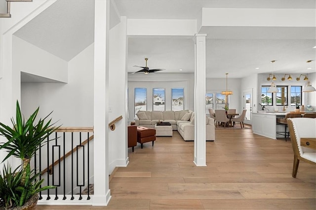 living area with recessed lighting, light wood-type flooring, ceiling fan, and decorative columns