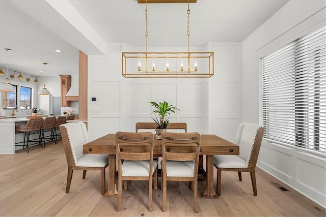 dining area with a decorative wall, recessed lighting, light wood-style flooring, and visible vents