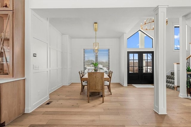 dining room with light wood-style floors, stairway, a notable chandelier, and french doors