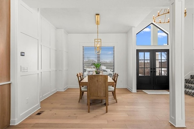 dining space with a chandelier, visible vents, light wood finished floors, and french doors