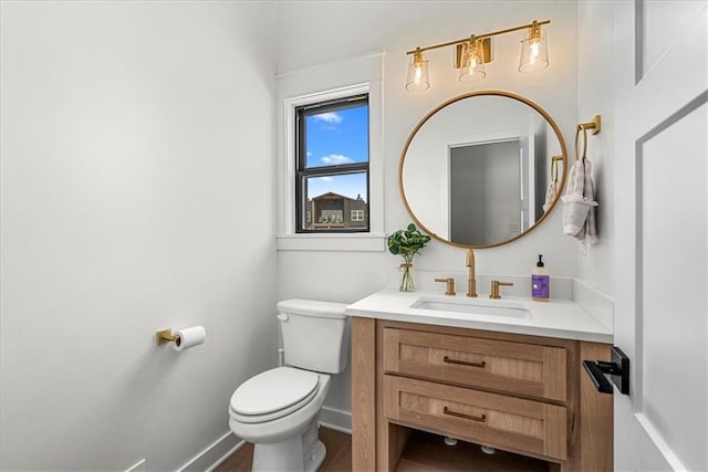 half bath with toilet, vanity, and baseboards