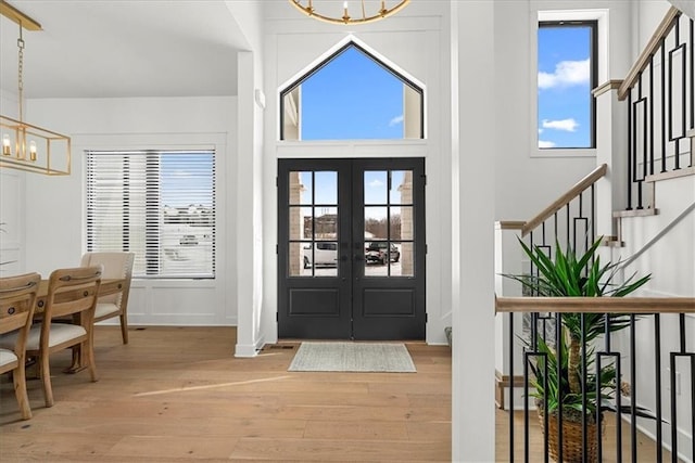 foyer entrance with stairway, plenty of natural light, light wood-style floors, and a chandelier