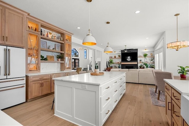 kitchen with high end white refrigerator, a kitchen island, light wood-style floors, and open shelves