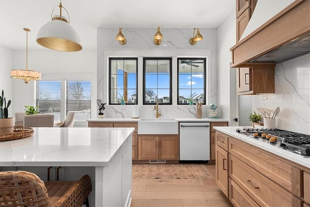 kitchen featuring a sink, backsplash, stainless steel gas stovetop, white dishwasher, and custom exhaust hood