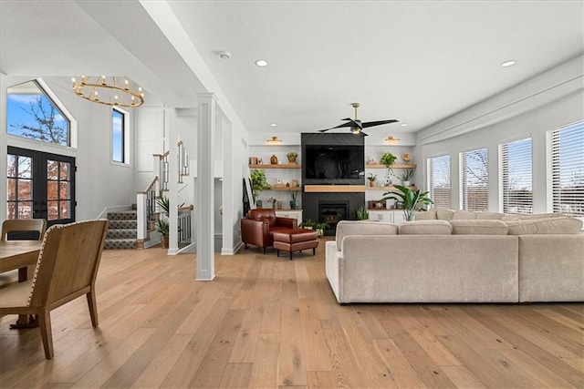 living room featuring stairs, a fireplace, light wood finished floors, and a healthy amount of sunlight