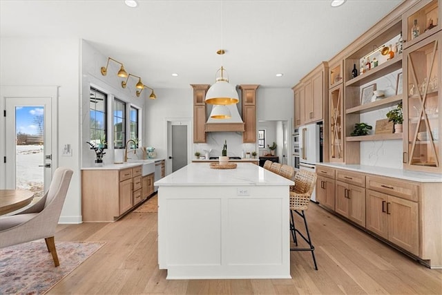 kitchen with open shelves, recessed lighting, a center island, and light wood finished floors