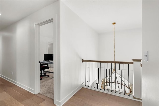 hallway featuring an upstairs landing, wood finished floors, and baseboards