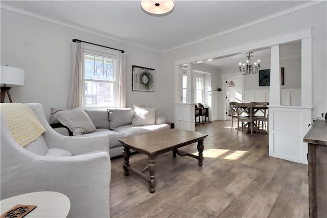 living area with a chandelier, ornamental molding, and wood finished floors