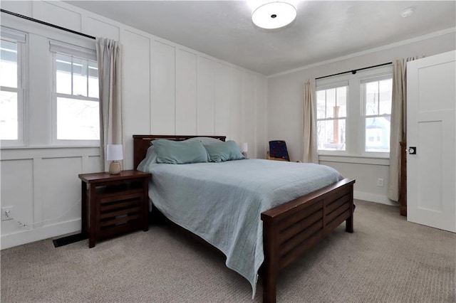 bedroom with a decorative wall, light colored carpet, and ornamental molding