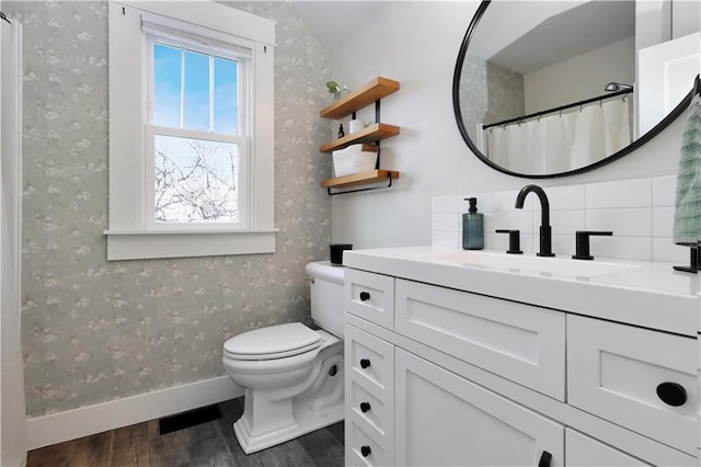 full bathroom with vanity, wood finished floors, baseboards, wallpapered walls, and toilet