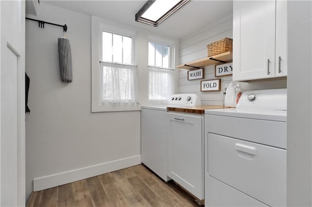 laundry area with wood finished floors, cabinet space, baseboards, and washing machine and clothes dryer