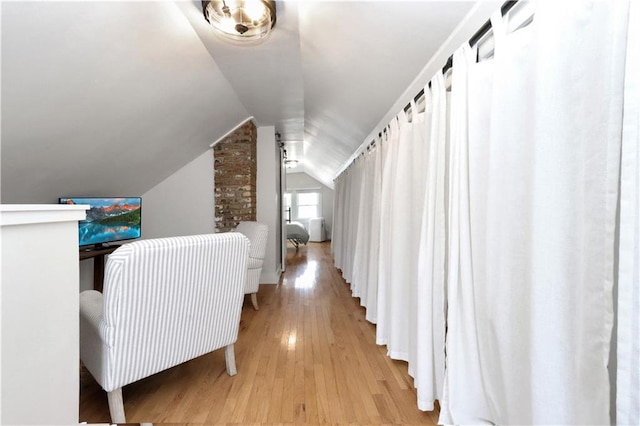 corridor featuring light wood finished floors and vaulted ceiling