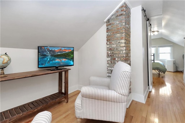 sitting room featuring light wood-style flooring, baseboards, and lofted ceiling