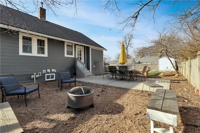 view of patio with a fenced backyard, entry steps, an outdoor structure, a fire pit, and a storage shed