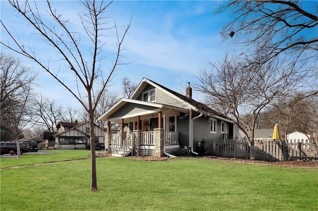 view of front of home with a chimney, covered porch, a front lawn, and fence