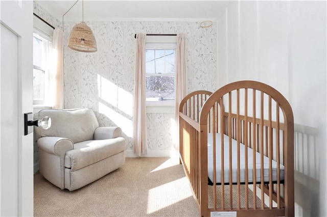 bedroom featuring a crib, multiple windows, wallpapered walls, and carpet floors