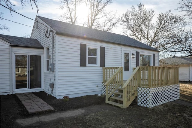 view of front of property featuring a deck and roof with shingles