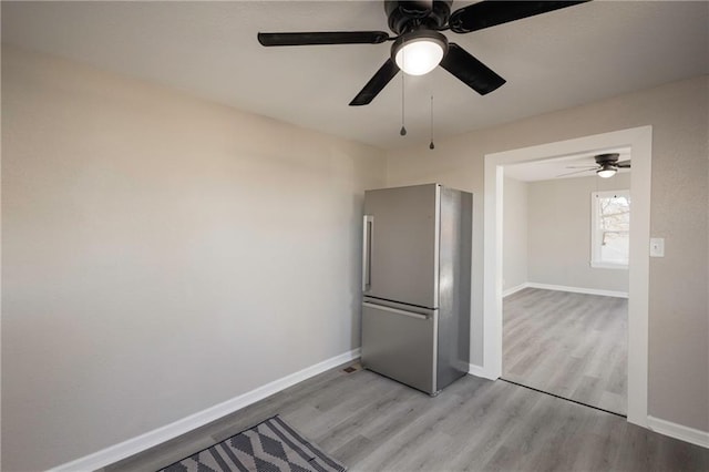 interior space featuring baseboards, freestanding refrigerator, and light wood-style floors