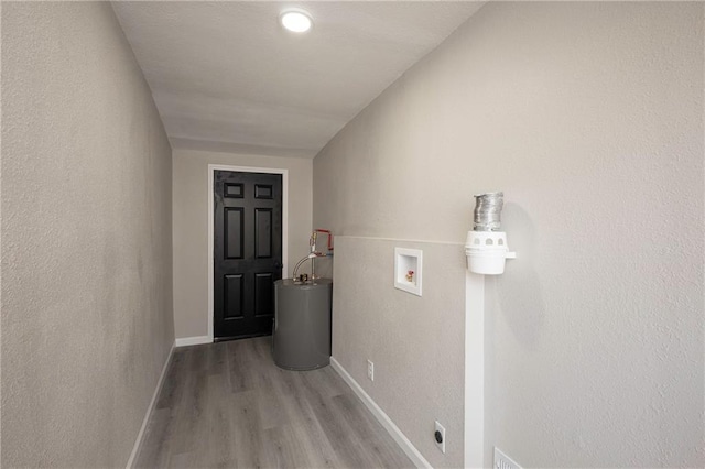 interior space with light wood-style floors, water heater, and baseboards