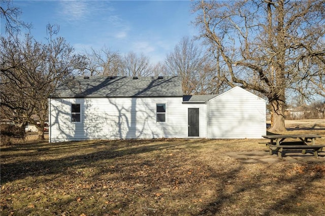 rear view of property featuring a shingled roof and a yard